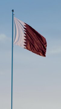 Qatar, Doha: Cinematic Vertical Waving National Flag Against Blue Sky