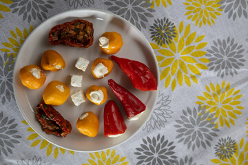 stuffed mini peppers and cheese cubes on yellow and gray patterned cloth