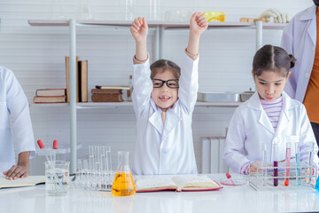 Group of multicultural students in lab coat uniform studying with Indian teacher writing report in laboratory, Iranian pupils girls scientist having fun in science class with microscope and test tube
