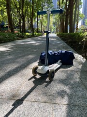 Kick Scooter and Travel Bag on Sunlit Pathway Ready for Trip