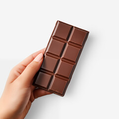 Obraz premium Hand holding a delicious milk chocolate bar isolated on a clean white background. Sweet treat for dessert, snack, or indulgence.