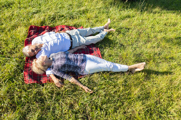 Senior couple relaxing on picnic blanket in grass