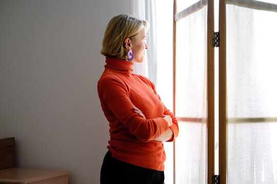 rear view of Mature woman looking out window thinking hopeful thoughts