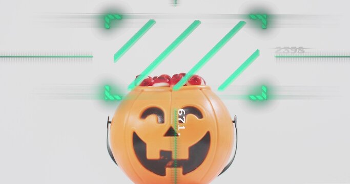 Displaying orange pumpkin bucket with black handles on tabletop showing glossy red candies AR 671