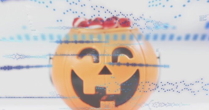 Displaying jack-o'-lantern container holding red candies on studio table, showing blue overlays