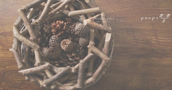 Displaying woven twig basket left on wood table, holding pine cones, showing white formulas overlay