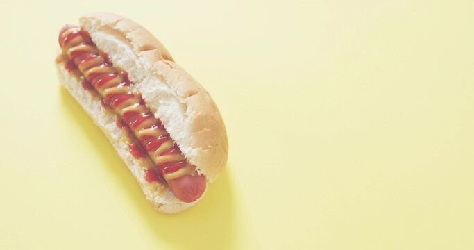 Fototapeta Sitting hot dog in soft bun on studio tabletop with mustard and ketchup drizzle, copy space