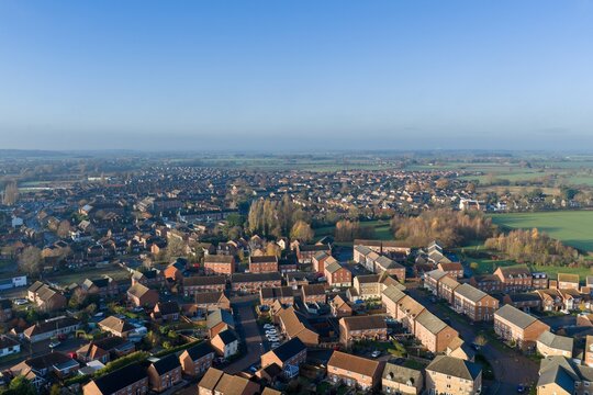 Aerial drone photo of the town of Batley in Wakefield in the UK, showing a typical British housing estate with rows of houses and homes near a public playing field on a sunny day in the winter time
