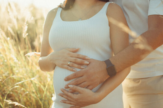 Pregnant couple holding baby bump outdoors