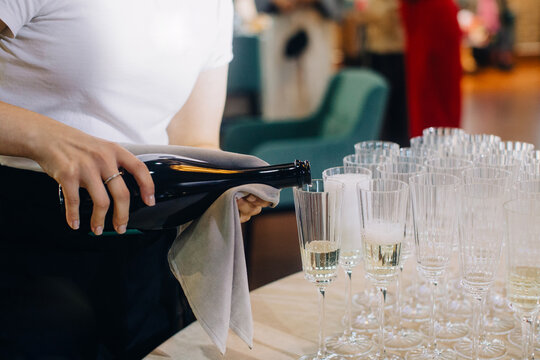 Hand pouring champagne into glasses at event