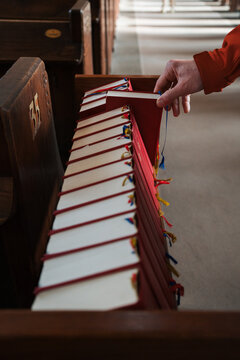 man pulling a bible out from a book shelf in church