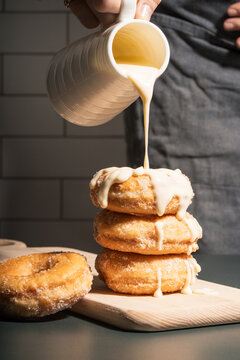 white chocolate being poured over stacked sugar donuts