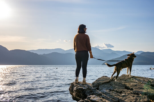 Woman and dog enjoying peaceful lake view and mountains at sunset