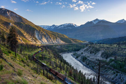Long cargo train traveling a winding railway line by Thompson river
