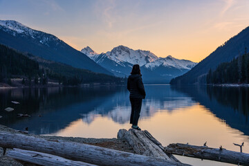 Woman standing on shoreline watching sunset over Duffey Lake