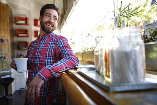 Happiness is time spent at his favorite cafe. A young man enjoying a cup of coffee in a coffee shop. - Powered by Adobe