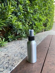 Spray Bottle on Bench with Green Hedge