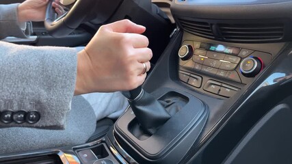 Close-up of woman hand shifting gears in a modern car while commuting through the city. Smooth everyday driving moment showing confidence, routine, and premium car interior details.