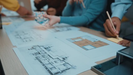 A group engages in a design session, examining architectural plans and color swatches on a table. Collaborative effort highlights creativity and professional consultation. SACTR