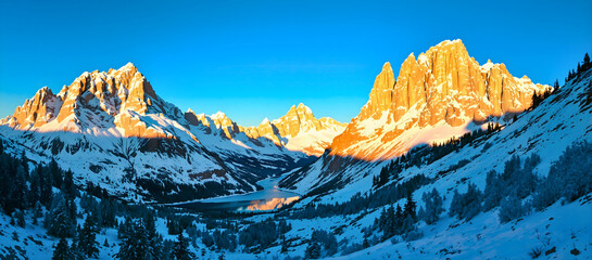 Panoramic view of Dolomite mountain peaks in beautiful morning light. Early winter scene with snow covered summits.