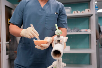 Experienced technician carefully shapes a prosthetic limb using a cutting instrument in a well-lit clinic. Ensuring a perfect fit, demonstrating attention to detail.