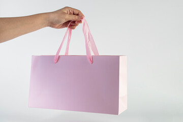 Pink paper shopping bag in hand on white background.