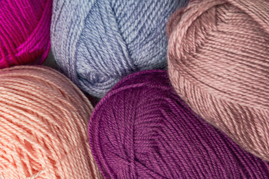 The multicolored background features tangles of lilac, pink and purple threads for crocheting or needlework.