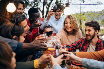Diverse friends celebrating together at dinner party outdoors with happy toasting moments
