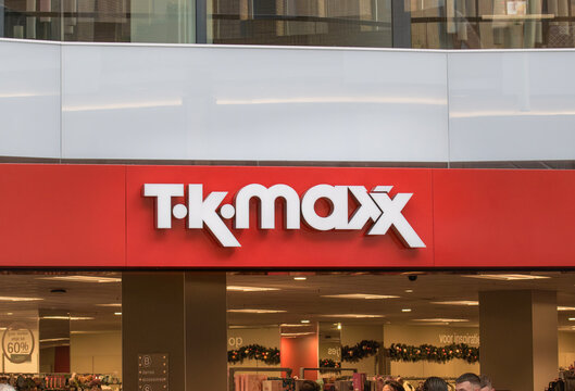 Store exterior sign for T K MAXX located in a busy shopping area during daylight hours with customers nearby