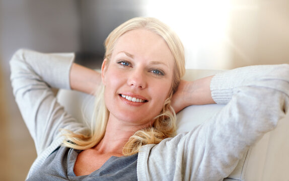 Happy, woman and relax with stretching on sofa for weekend break, lazy morning and flare. Portrait, person and comfortable with smile in home for rest, day off and peaceful afternoon in living room