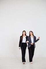 Two Asian women dressed in business attire posing on a clean white background, representing modern corporate roles, confident teamwork, and professional collaboration for office and company branding v