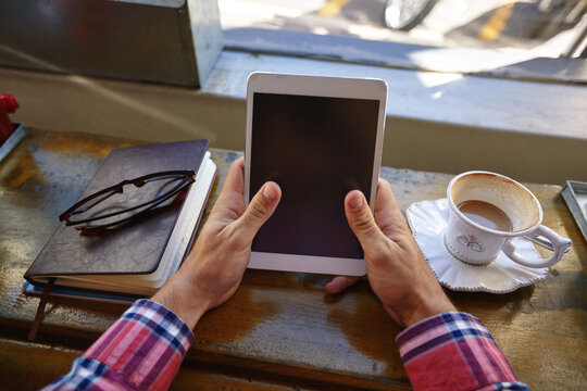 Person, hands and cafe with tablet screen for advertising, marketing or network connection. Closeup, user or technology display with book for online interface or UX on mockup space in coffee shop - Powered by Adobe