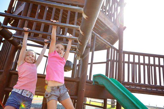 Happy girl, friends or hanging with monkey bars for playful childhood or fun outdoor summer. Kid, children or climbing with sunshine on jungle gym for youth, development or playing at park playground