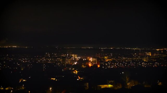 Time-lapse footage of rolling power outage in Ukraine, with city electricity supply gradually returning to the windows residential buildings house and streets. dark black night cityscape top view 4k.