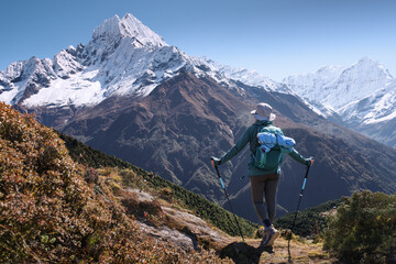 Young female backpacker admiring on trail during sunny day on her trek to Everest Base Camp in Nepal.