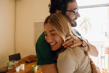 A man hugs a woman who is standing close by and they laugh