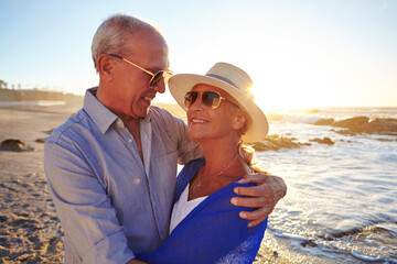 Happy, hug and senior couple by beach on summer vacation, getaway or weekend trip together. Sunset, love and old man with woman for embracing with care, connection or bonding by ocean on holiday.
