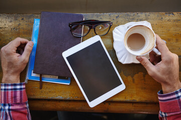 Person, hands or tablet screen with coffee in cafe, above for creative journalism or advertising. Freelancer, journalist and technology display with books or cup for remote work in restaurant