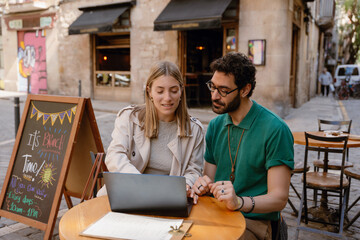 Man and woman looking at laptop and sitting at table