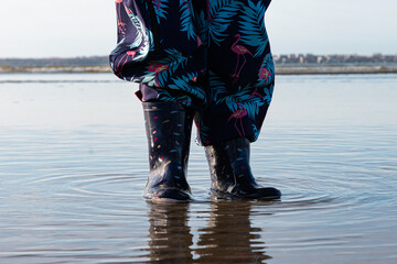 Deux pieds d'enfant en bottes créant des ondulations dans l'eau