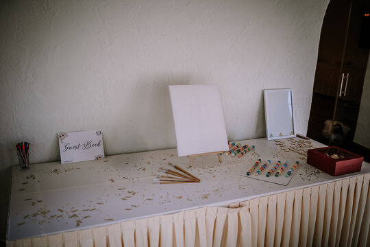 Elegant wedding guest book table featuring blank canvas, decorative items, and colorful pens, creating a welcoming atmosphere for guests to share their thoughts and memories