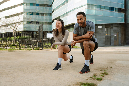 Male and female athletes smiling and stretching their legs while doing lunges