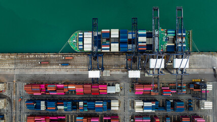 Aerial top view of industrial port terminal with cranes loading cargo containers