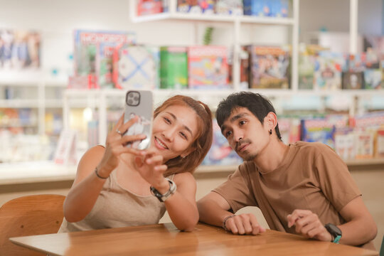 Couple Use Smartphone Device, while Sitting on a Couch in the Cozy Apartment. Boyfriend and Girlfriend Shopping on Internet, Watching Funny Videos, Use Social Media, Streaming Service.