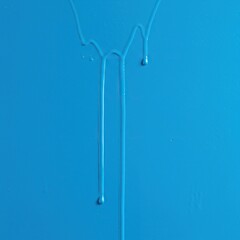 Vibrant blue paint drips slowly down a freshly coated surface, indicating it is still wet and should not be touched. A caution for new finishes ,liquid ,careful ,texture