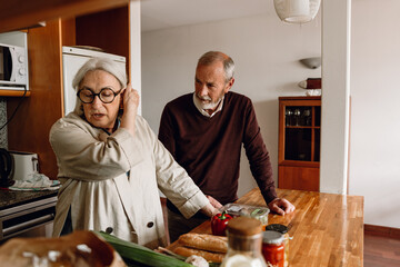 A woman fix her hair and talks to a man standing next to her at the table