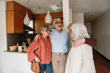 A man laughs and hugs a woman while they listen to a man and woman friends hugging across from them