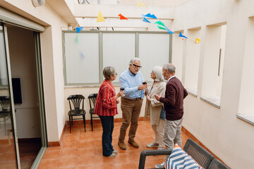 A man is talking to a group of three friends who are listening while they stand and hold glasses