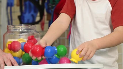 A neurologist and traumatologist helps a child develop motor skills through play. Rehabilitation and development of children with autism spectrum disorders. Hands close-up