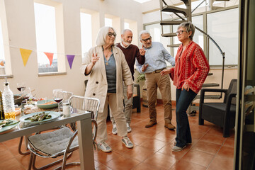 Group of four friends smiling and dancing between table and chairs
